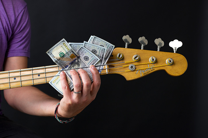 Picture of a bass with dollar bills under the strings