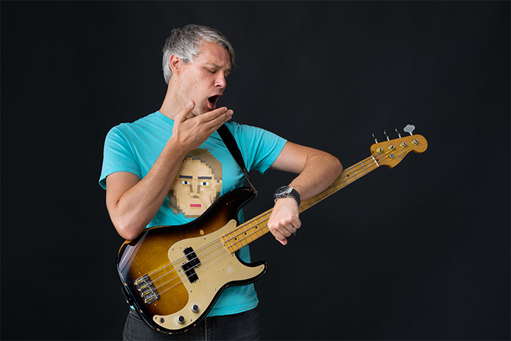 Gio holding a bass, yawing and looking at his watch